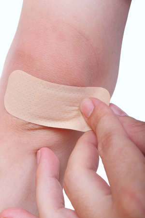 hand putting a band aid on kid's knee