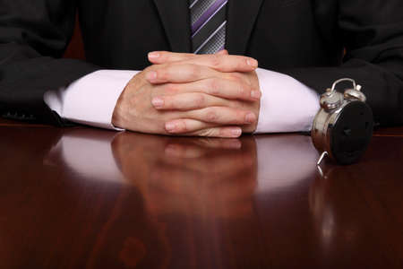  clock in front of formally dressed man at a desk officeの写真素材
