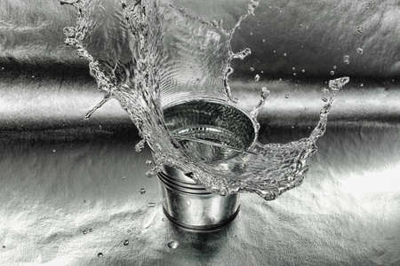 high speed image of tin bucket with water hitting the ground