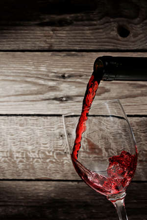 wine being poured into glass against wooden backgroundの写真素材