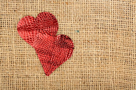 two red glossy hearts on burlap textureの写真素材