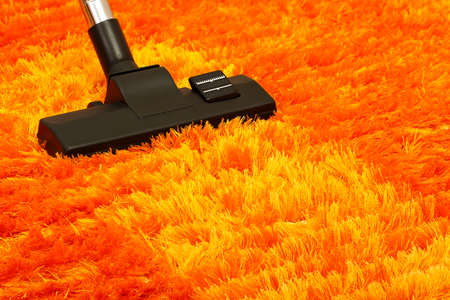 vacuum cleaner on orange fluffy carpet closeupの写真素材