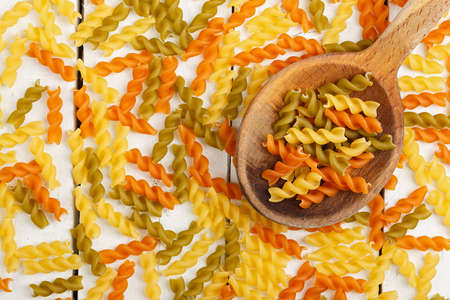 ladle with colorful fusilli pasta on old wooden tableの写真素材