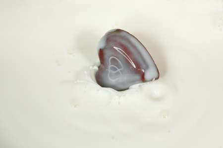 chocolate heart falling into milk surfaceの写真素材