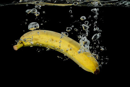 closeup of  banana sinking into water on black