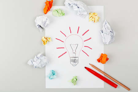 lightbulb surrounded by crumpled notes on desk surfaceの写真素材