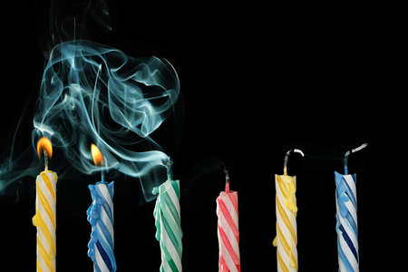 birthday candles that have just been blown out with smoke on black backgroundの写真素材