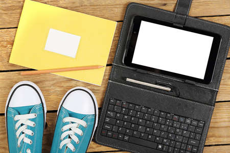 sneakers with tablet computer and notebook on wooden surface