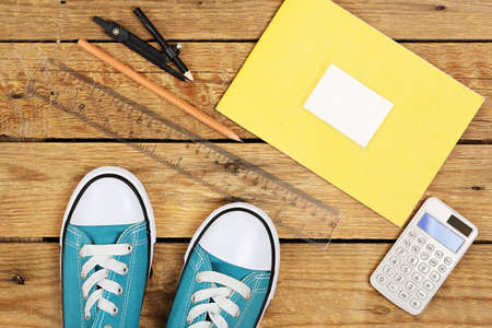 pair of sneakers with school items on wooden surfaceの写真素材