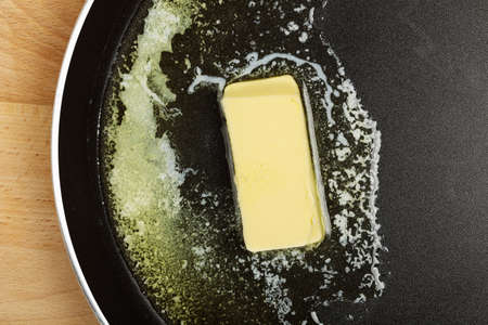 piece of butter while melting in frying panの写真素材