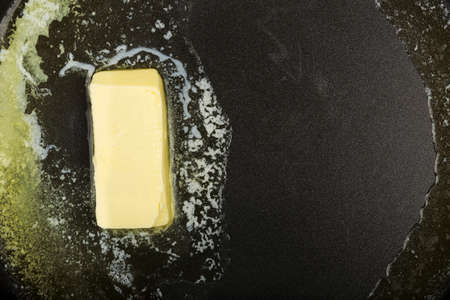 piece of butter while melting in frying panの写真素材