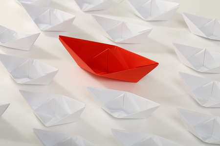 red paper boat among smaller white onesの写真素材