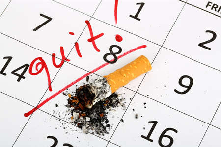 stubbed out cigarette on calendar, quit smoking conceptの写真素材