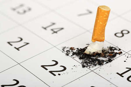 stubbed out cigarette on calendar, quit smoking conceptの写真素材