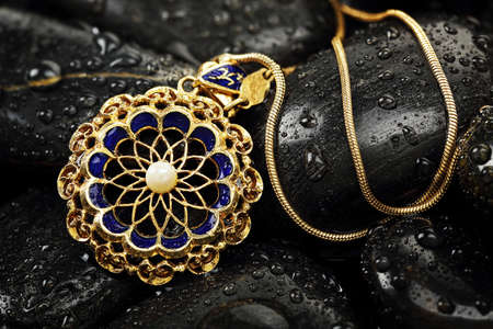 vintage pendant on black rocks with water dropsの写真素材