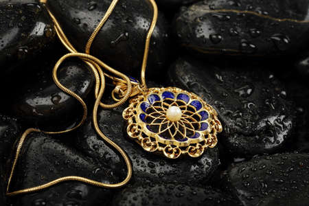 vintage pendant on black rocks with water dropsの写真素材