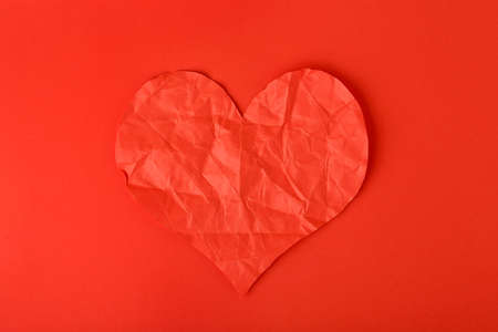 crumpled paper heart on red surface, heartbroken conceptの写真素材