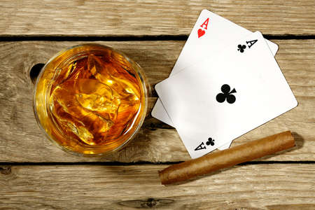 whiskey with playing cards and cigar on old wooden surfaceの写真素材