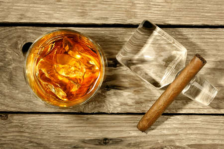 whiskey on the rocks with cigar on weathered wooden surfaceの写真素材