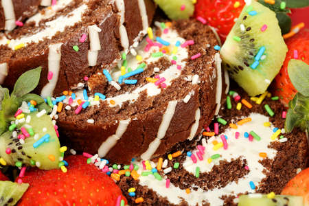 sliced cake roll surrounded by strawberries and kiwi fruit