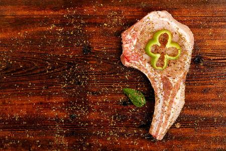 raw pork steak with oregano and pepper slice on wood