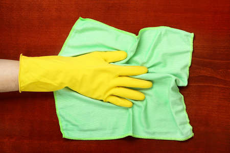 hand in rubber glove with microfiber cloth wiping the tableの写真素材