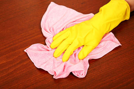 hand in rubber glove wiping wooden surface