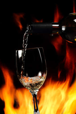 pouring white wine by the fireplaceの写真素材