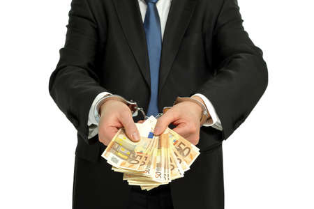 man in suit with handcuffs and holding banknotes