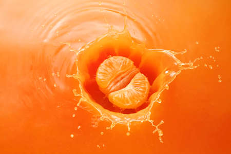 peeled tangerine splashing in orange juiceの写真素材