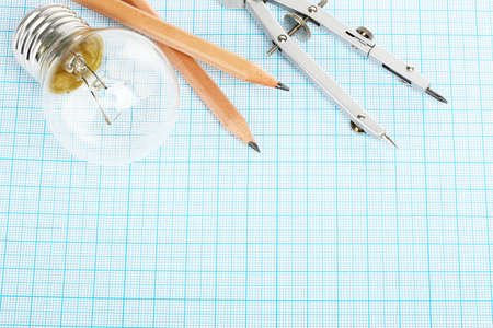 light bulb, pencils and compasses on millimeter paperの写真素材