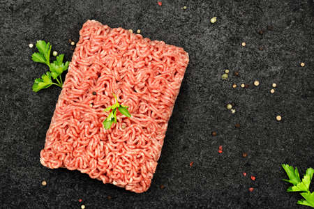  raw minced meat with parsley and pepper on black stoneの写真素材