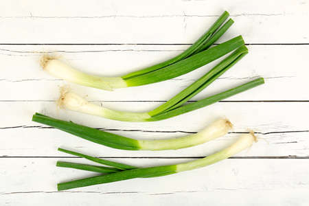 green onions or scallions on white wooden planksの写真素材