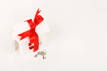 white cardboard house with ribbon and keys on white surfaceの写真素材