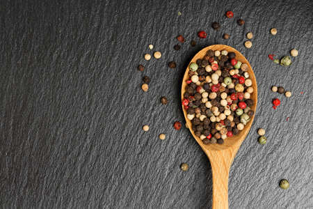 ladle with a mix of peppercorns on black stoneの写真素材