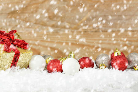 xmas baubles and giftbox on snow against woodの写真素材