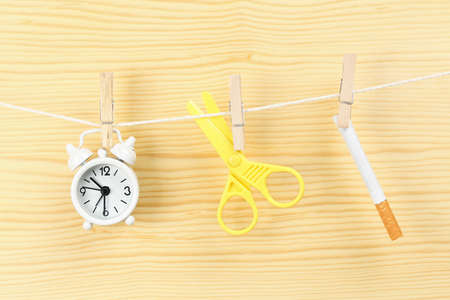 time to quit smoking concept with clock, scissors and cigarette on clotheslineの写真素材