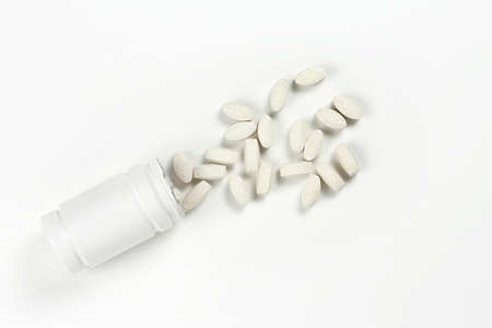 top view of white bottle and tablets on white surfaceの写真素材