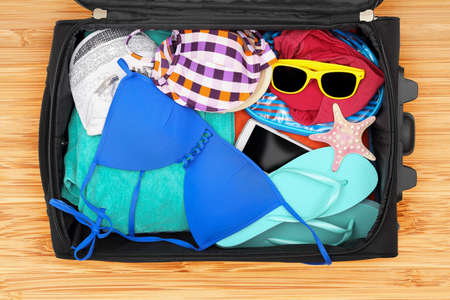 open suitcase on floor with beach accessories, top viewの写真素材