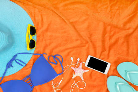Essential items for the beach on orange towel with copy spaceの写真素材