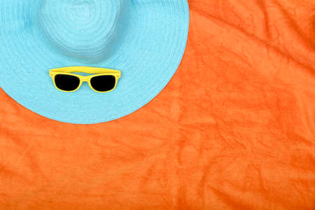 hat and sunglasses on orange beach towel with copy spaceの写真素材