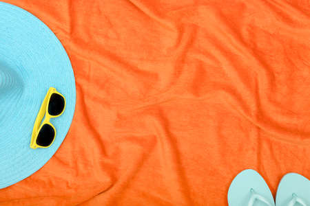 hat and sunglasses on orange beach towel with copy spaceの写真素材