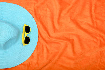 hat and sunglasses on orange beach towel with copy spaceの写真素材