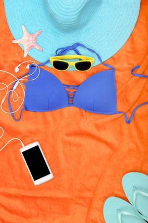 essential items for the beach on orange towel with copy space