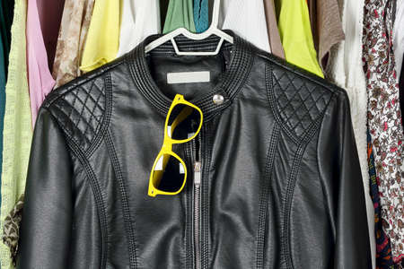 black leather jacket and sunglasses in front of other female clothing