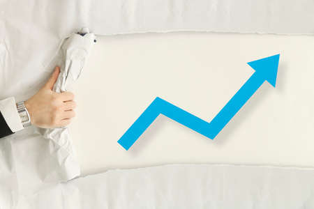 male hand ripping a paper sheet revealing graphs showing growthの写真素材