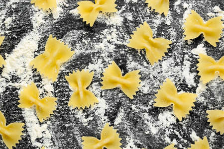 raw farfalle pasta with flour on black stone textureの写真素材