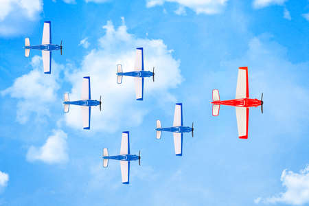 red plane leading a formation of smaller planes on paper surface with clouds, leadership conceptの写真素材