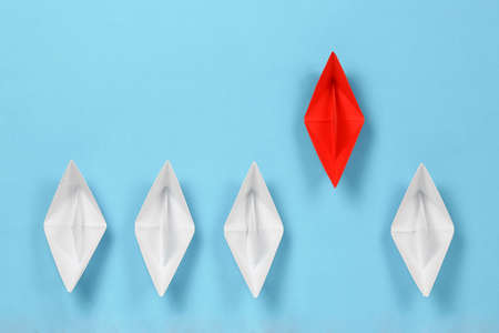 red paper boat leading the race against white paper boats, abstract concept
