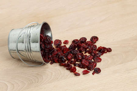 bucket of dried cranberries on wooden surfaceの写真素材